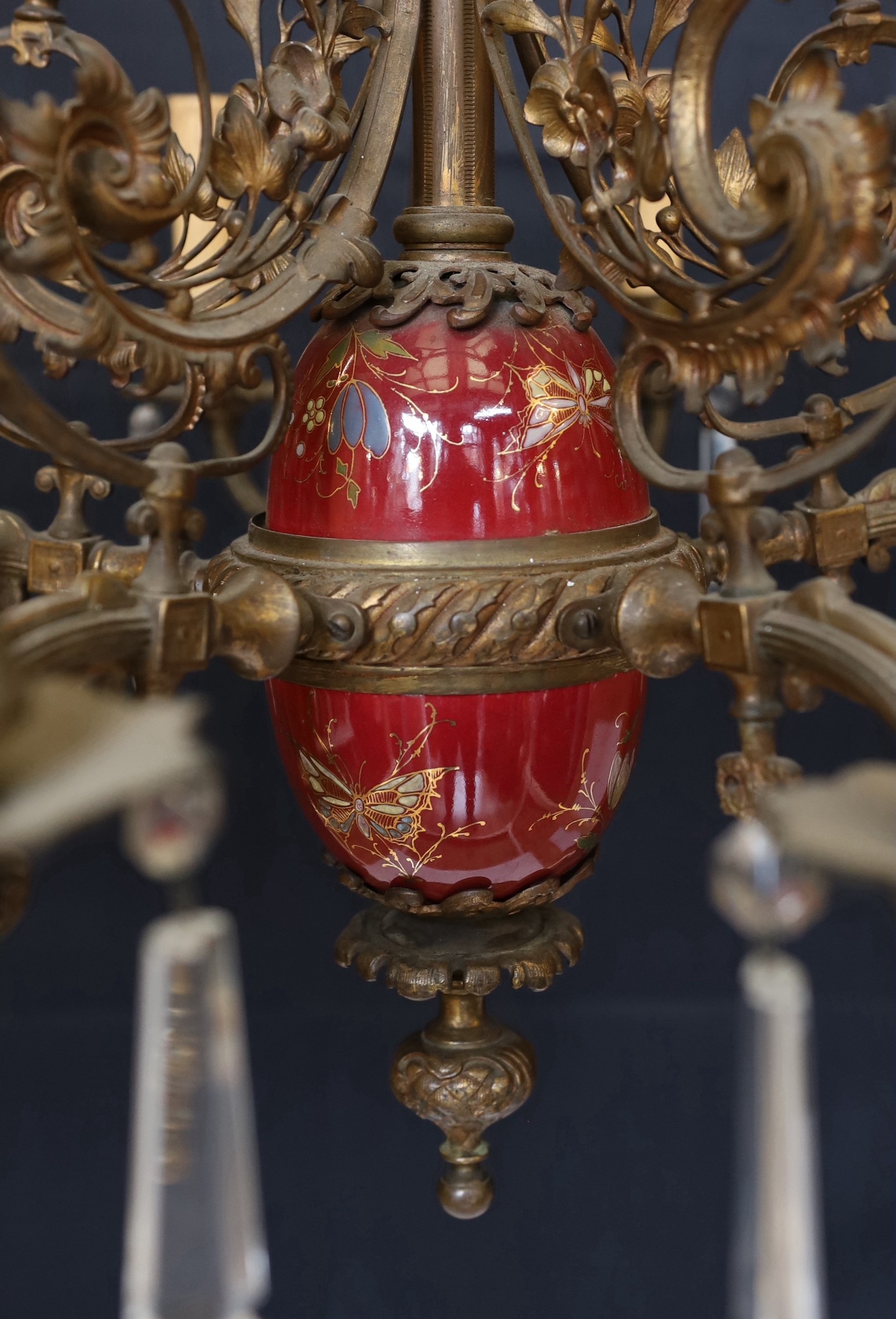 A Victorian bronze ten light gasolier with ornate scrolling foliate frieze and central ceramic stem, hung with spear shaped drops, later fitted for electricity, height 92cm. width 60cm